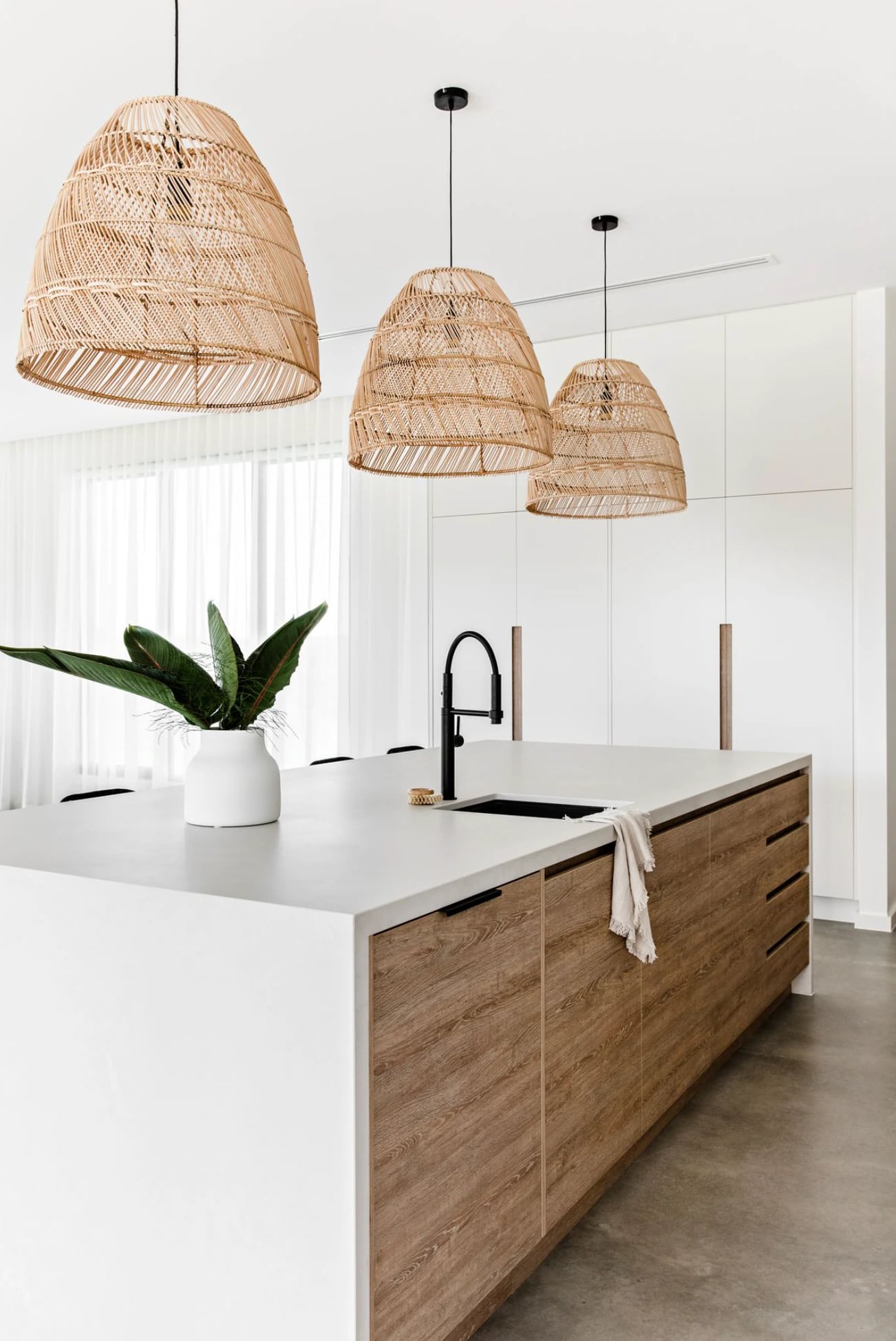 Kitchen with three rattan PītasLampas ceiling lamps, warm lighting.