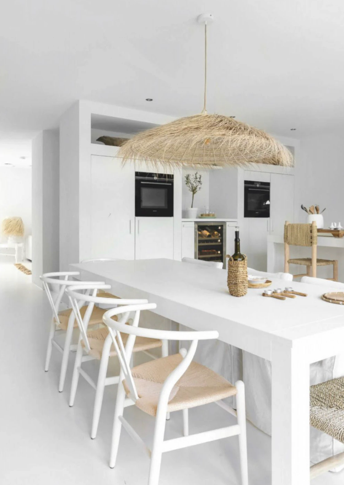 PītasLampas reed woven ceiling lamp in all-white kitchen, warm light.